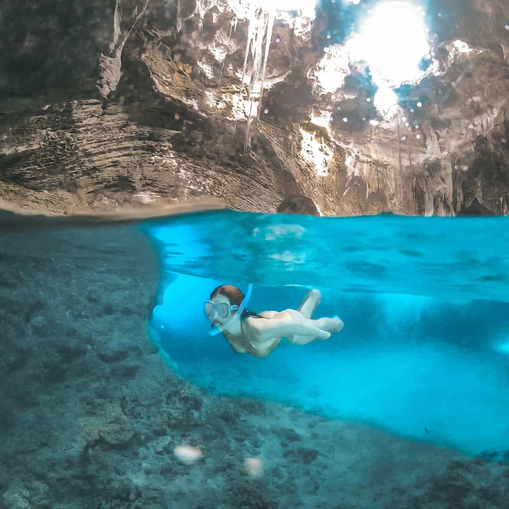 Snorkeling inside Thunderball Grotto, near Staniel Cay in the Exumas. This grotto was made famous by the James Bond movie, Thunderball. Best places to see in Exuma, Bahamas.