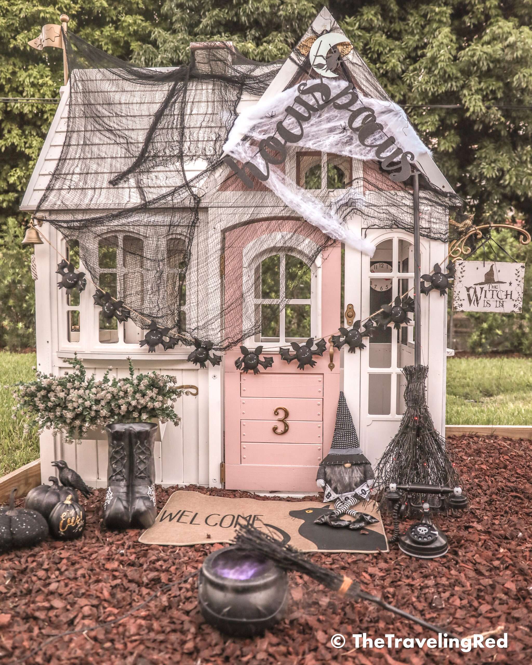 Hocus Pocus Halloween Playhouse - Halloween Decorations to turn a renovated outdoor playhouse into a spooky witches home perfect for playtime during the month of October | added spider webs, bats, witches boots and broomstick, a cauldron and the cutest witch costumes | remodeled DIY pink and white playhouse #playhouse #halloween #witch