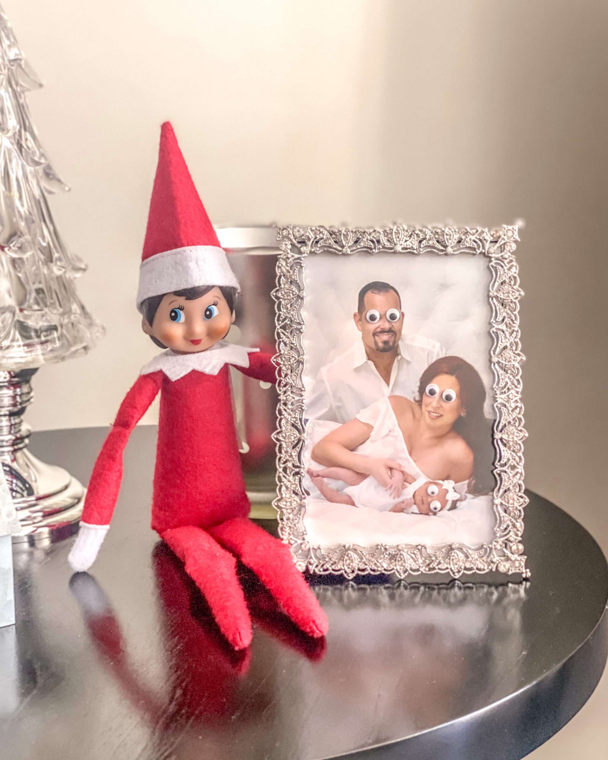Googly eyes on family photos. Fun & easy Elf on the Shelf ideas for your toddler or little kid. Quick to setup and lots of naughty and nice ideas, perfect to bring some Christmas magic to your home. #ElfOnTheShelf #ElfIdeas #ElfOnTheShelfIdeas #Christmas #ChristmasMagic