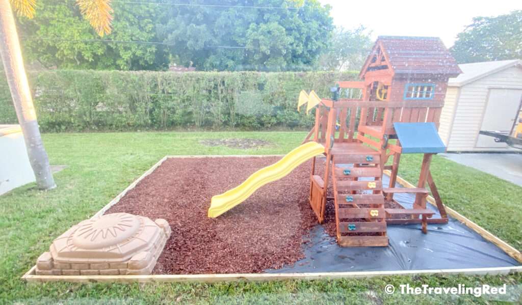 How to build a custom backyard playground with rubber mulch. Step 6 is to add the mulch. We chose red rubber mulch for aesthetic but to also keep it soft for the kids. This space will fit our swingset, playhouse, sandbox or any other outdoor toys you plan to include. Perfect little outdoor play space for your kids to enjoy playing outside.