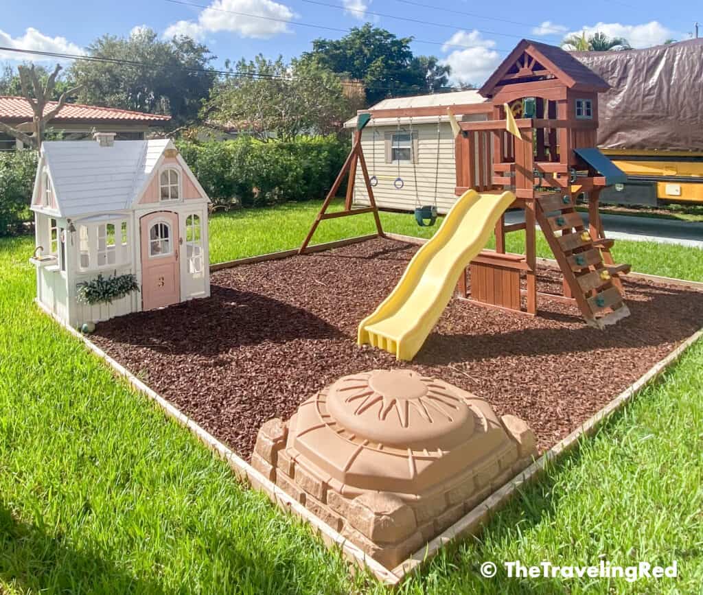 How we built a custom backyard playground with rubber mulch for our swingset, playhouse and sand box. Perfect little outdoor play space for your kids and it's soft on the feet.