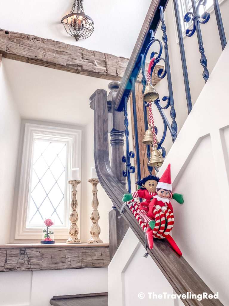 Naughty Elf on the shelf sledding down the staircase railing on some candy canes. Fun and easy elf on the shelf ideas for a naughty elf that are quick and easy using things you have at home.