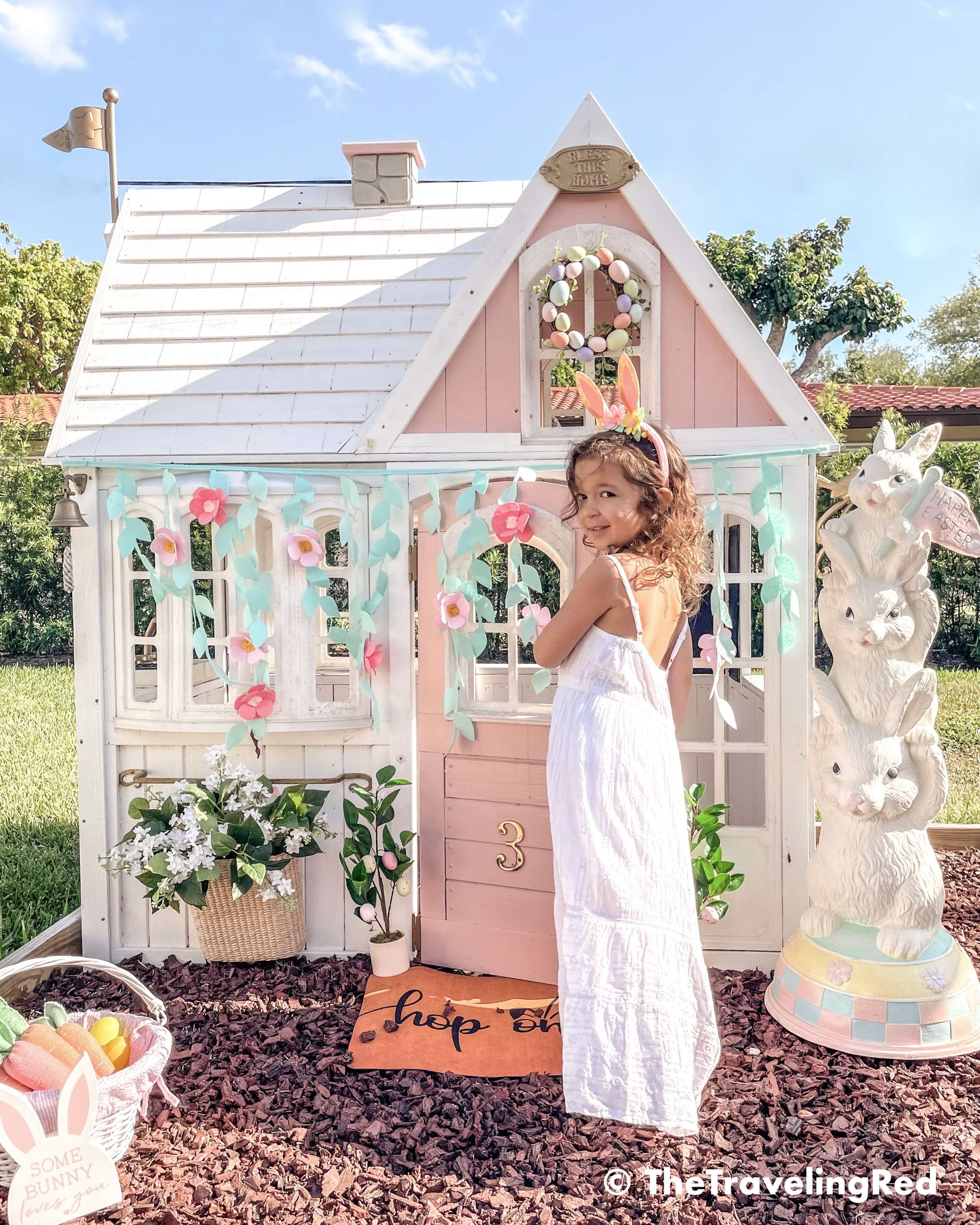 Little girls outdoor playhouse decorated for easter and spring. My daughters outdoor pink and white playhouse that my husband DIY ed for her custom backyard playground. It's the perfect backdrop for any photo shoot. I do seasonal photo shoots for each holiday in front of her house and decorate for the holiday.